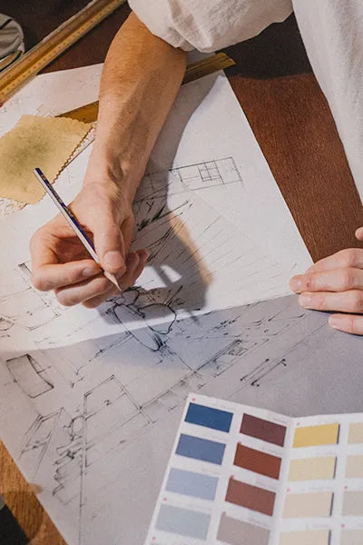 Person working on a design project with blueprints and color swatches.
