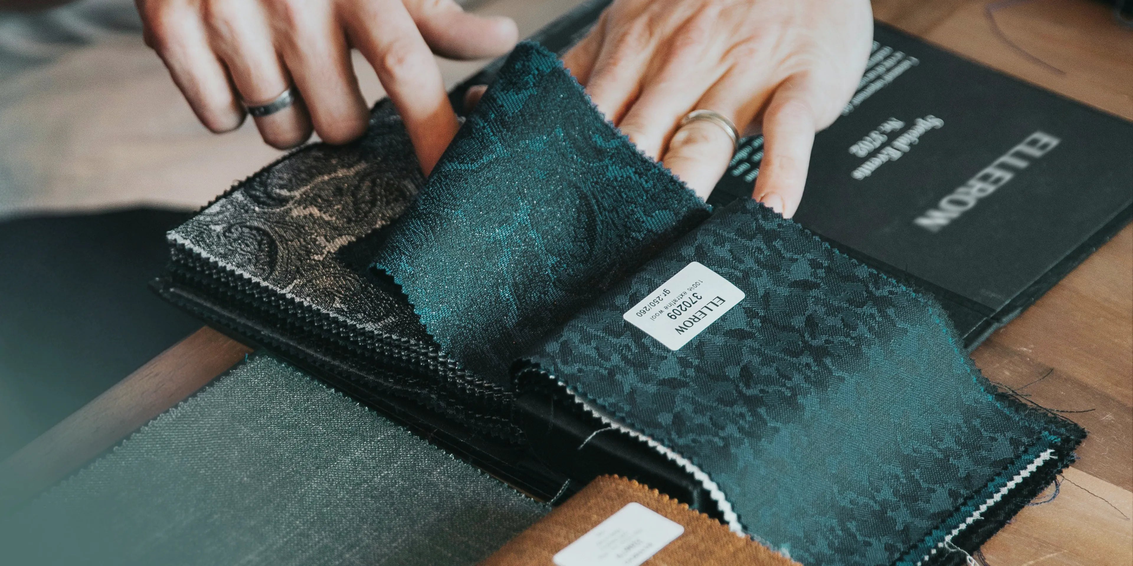 Person holding a textured green fabric sample with a visible brand label.