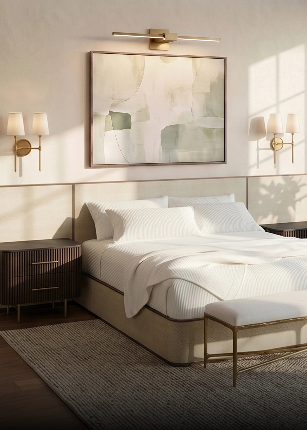 A modern bedroom scene featuring a bed dressed in white linens, a beige upholstered bed frame, a matching bench, dark wood nightstands, wall-mounted sconces, and a large abstract framed artwork above the headboard.